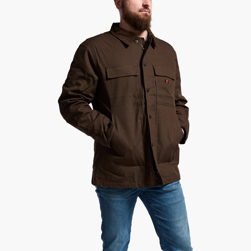 Man wearing a brown jacket with multiple pockets on a white background