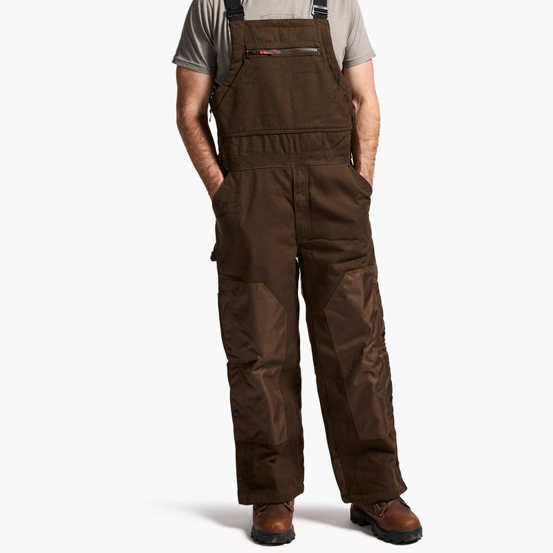 Brown bib overalls worn by a person on a white background