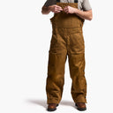 Brown bib overalls worn by a person on a white background