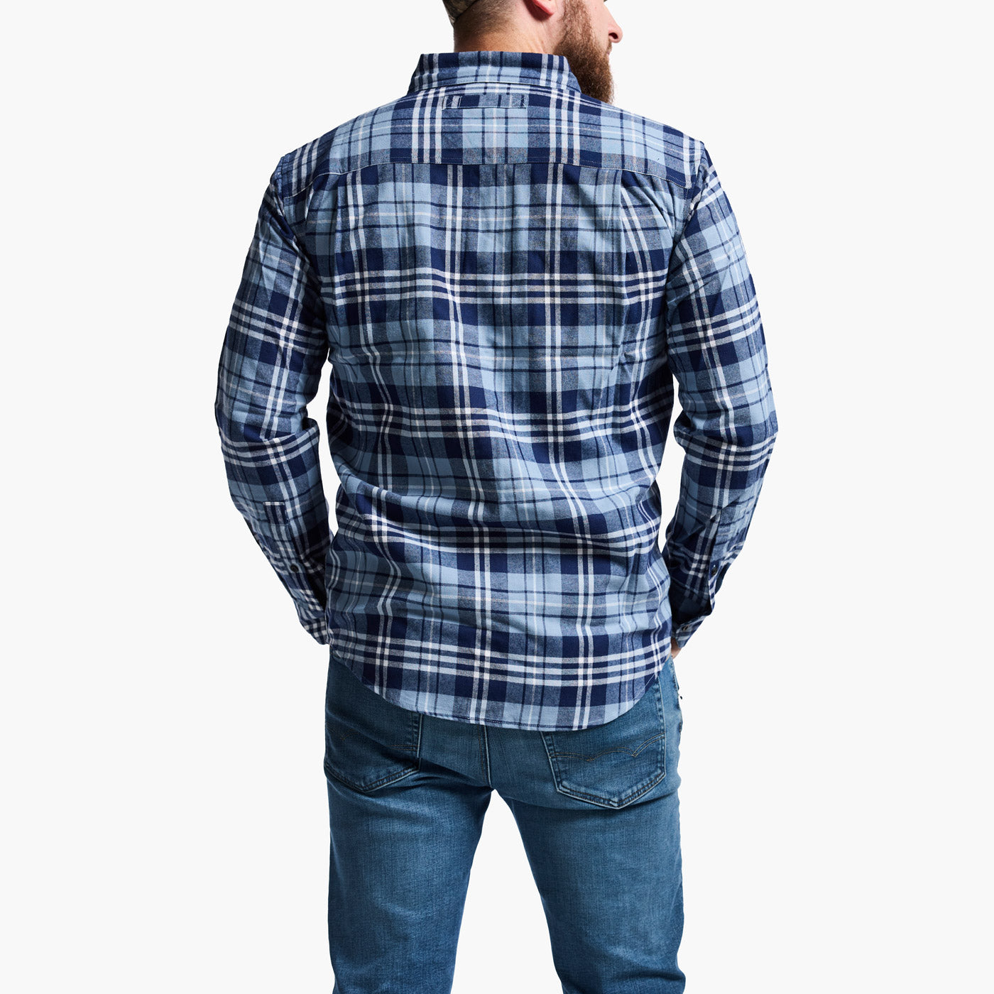 Man wearing a blue plaid shirt and jeans on a white background