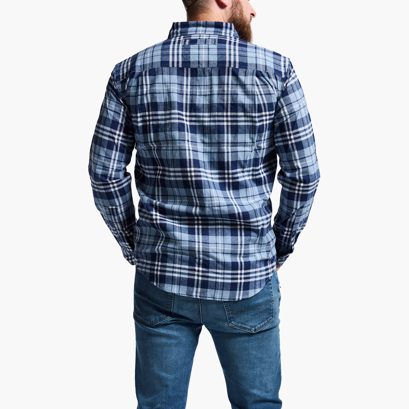 Man wearing a blue plaid shirt and jeans on a white background