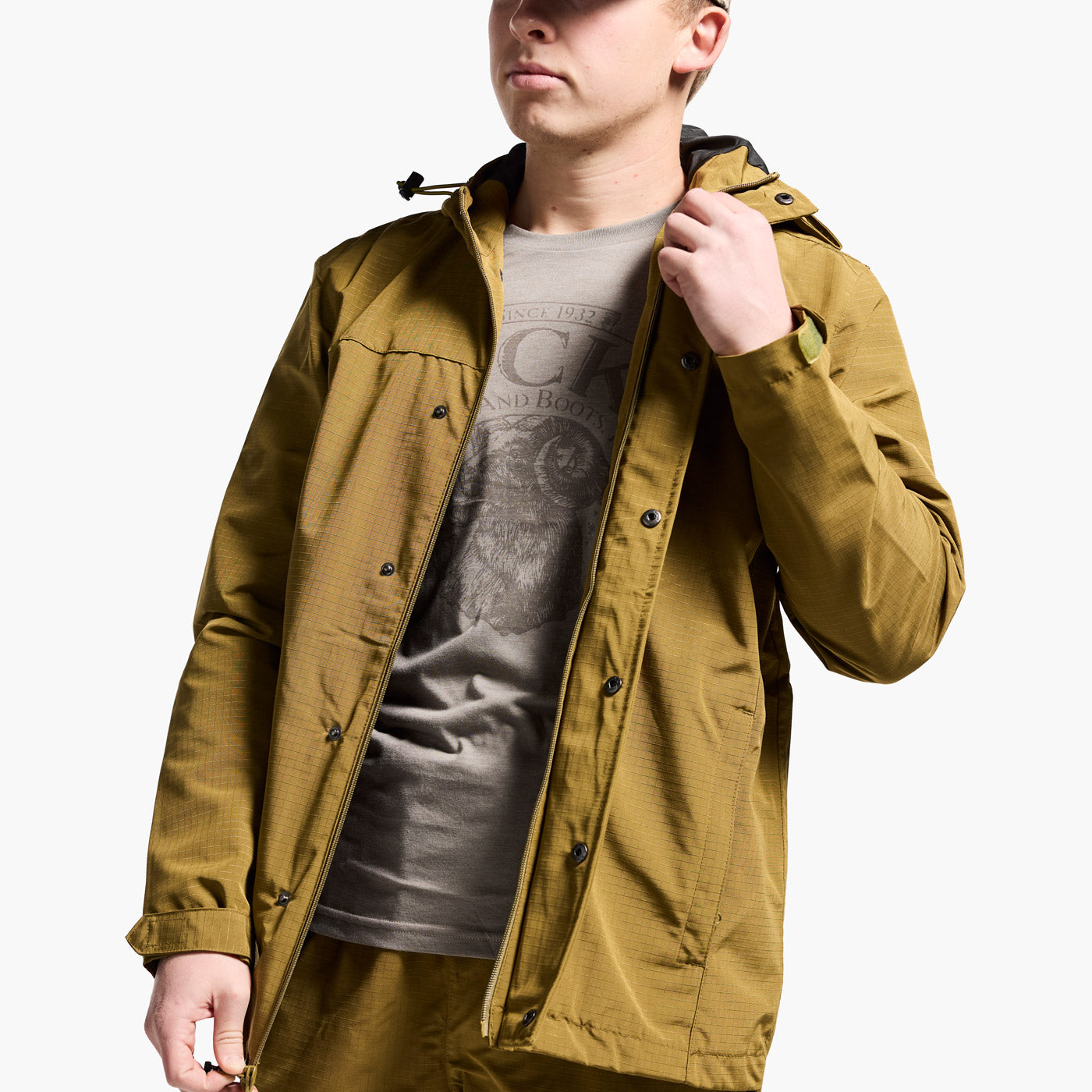 Person wearing a mustard yellow jacket over a gray t-shirt on a white background